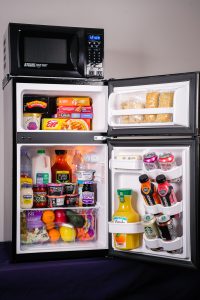 an open dorm-sized refrigerator stocked with food and drinks